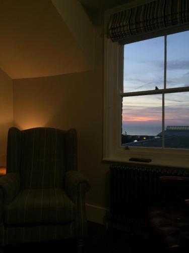 a room with a chair and a window with the sunset at The Seaview Snug in Whitstable
