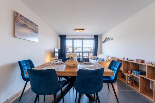 une salle à manger avec une table en bois et des chaises bleues dans l'établissement L'écrin des sapins, à Aime La Plagne