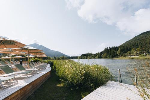 a row of chairs and umbrellas next to a lake at Hotel Seespitz Superior - Adults Only in Seefeld in Tirol