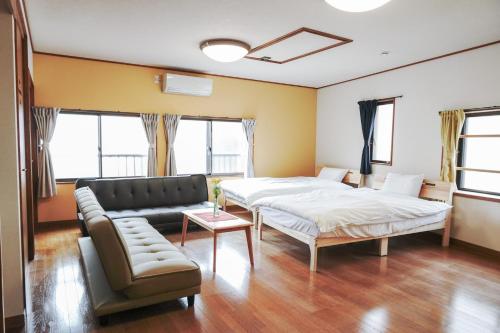 a living room with two beds and a couch at Oyado HALUBALL in Takayama
