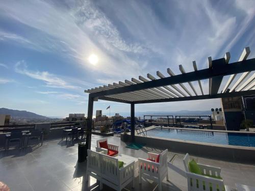a rooftop patio with a pool and tables and chairs at Mass Paradise Hotel in Aqaba