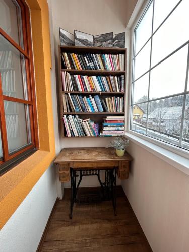a book shelf with a desk in a room with a window at Penzion Aurelia Donovaly in Donovaly