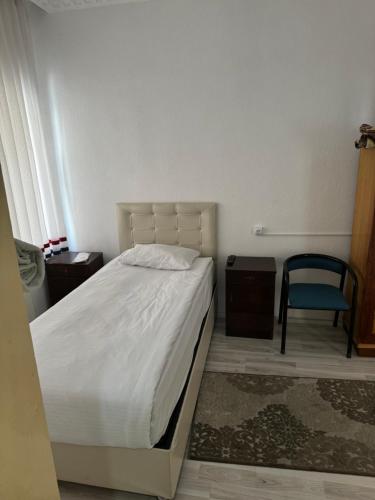 a bedroom with a bed and a blue chair at Gümüş Hotel in Ortahisar