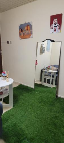 a room with green carpet and a table and a mirror at MAMA DELiGHT HOME in Abu Dhabi