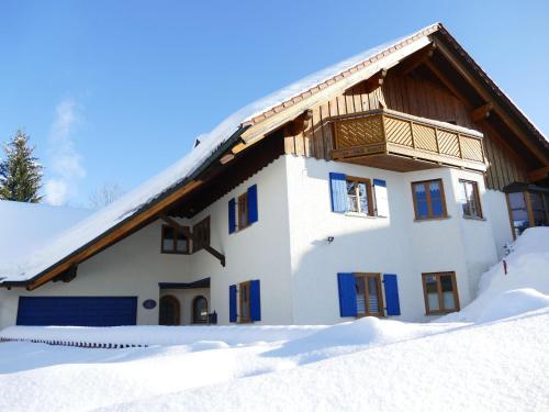 a house with blue windows in the snow at Ferienwohnung am Kneipp-Park in Scheidegg