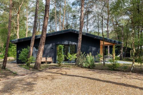 a house in the woods with a black roof at Luxe familiehuis in parkbos in Giethmen