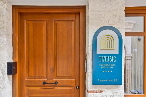 a door with a sign next to a building at Mansio Boutique Hotel in Rethymno Town