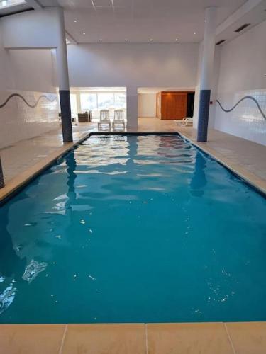 une grande piscine avec de l'eau bleue dans un immeuble dans l'établissement Appartement au ski spacieux pour 7P, piscine sauna, à La Foux d'Allos