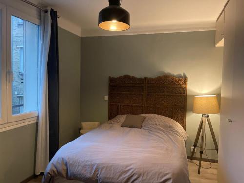 une chambre avec un lit, une lampe et une fenêtre dans l'établissement Appartement Le Raincy, à Le Raincy