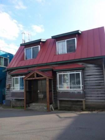 una casa con techo rojo encima en Emina Backpackers, en Otaru