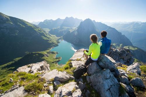 a couple sitting on the edge of a mountain overlooking a lake at City Apartments Bludenz in Bludenz