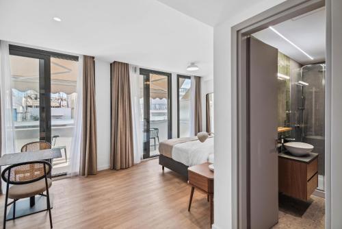 a bedroom with a bed and a table and a bathroom at Limehome Piraeus Olive in Piraeus