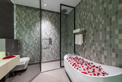 a bathroom with a tub covered in red roses at Ewaa Express Hotel - Abha in Abha