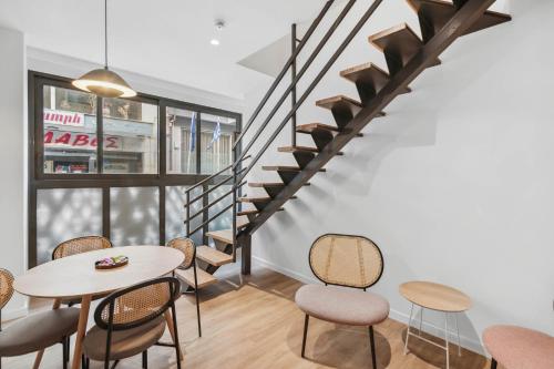 a room with a table and chairs and a staircase at Limehome Piraeus Olive in Piraeus