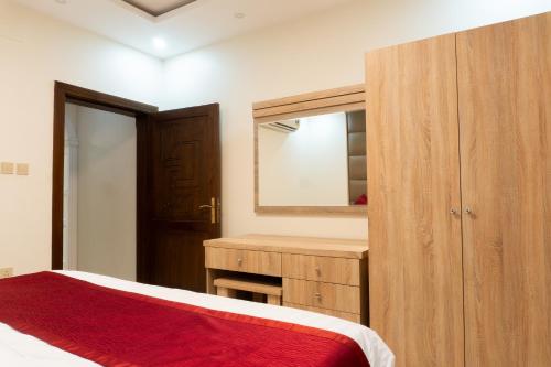 a bedroom with a wooden cabinet and a mirror at Dyar Sultana - 10 Mins Drive to Al Masjed Al Nabwi in Sulţānah