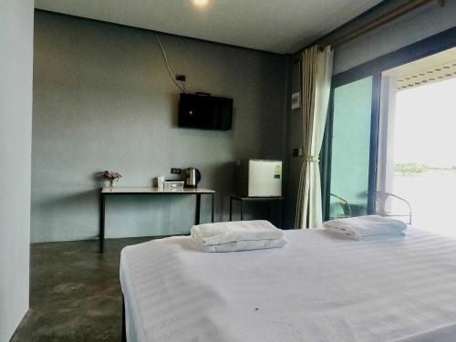 a bedroom with a large white bed with a window at OYO 75530 By the dam cafe and farmstay in Plai Phraya