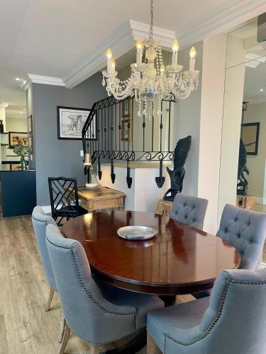 a dining room with a table and chairs and a chandelier at Romney Park Luxury Apartments by The Stay Collection in Cape Town