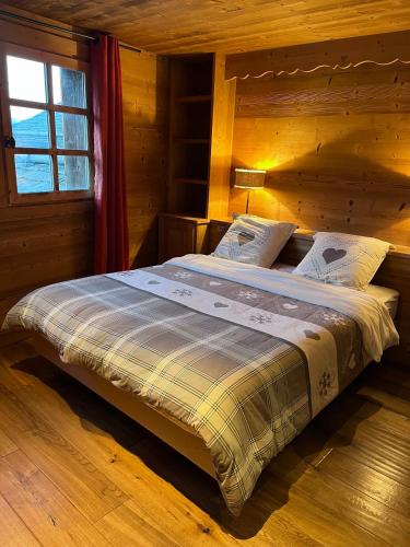 une chambre avec un lit dans une cabane en bois dans l'établissement Cosy base to ski the 3 Valleys, à Les Allues