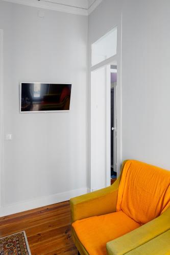 an orange couch in a living room with a tv at Angels Homes n.27 1ºandar, Bairro tipico, Centro cidade in Lisbon