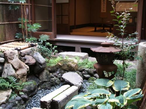 a garden with a fountain and rocks and a building at Inn Kawashima in Kyoto