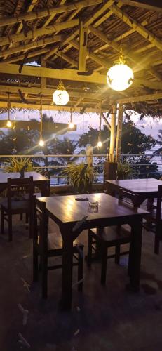 a restaurant with wooden tables and benches and lights at White Surfing Beach Resort in Unawatuna