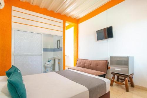 a bedroom with a bed and a tv and a couch at Biohotel Caribe Green in Santa Marta