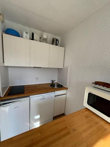 une cuisine avec des armoires blanches et un micro-ondes dans l'établissement Super studio à la résidence Cantoural, à Le Plan