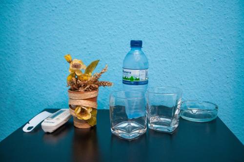 a bottle of water and two glasses on a table at Hotel 4You in Tbilisi City