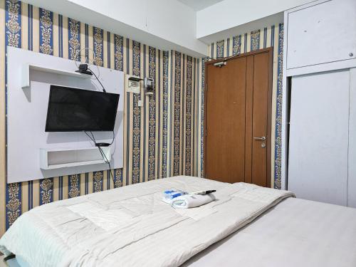 a room with a bed with a tv on a wall at Apartemen Green Lake View Ciputat by Twin Property in Pondokcabe Hilir