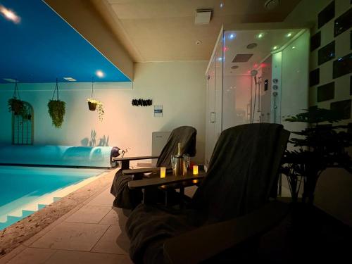 a room with a pool and two chairs and a table at B&B Wellness Soest in Soest
