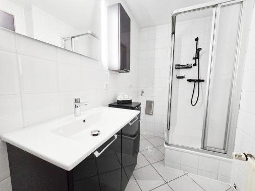 a white bathroom with a sink and a shower at Apartment mit Aussicht über Osterode in Osterode