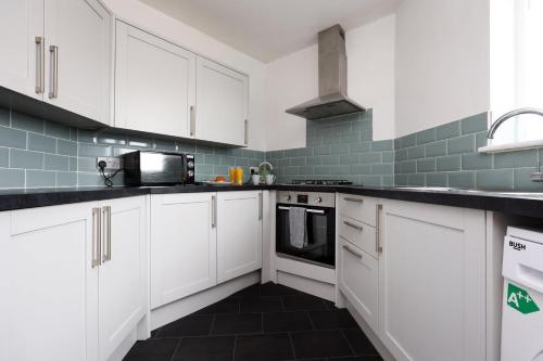 a kitchen with white cabinets and a black floor at Escape to Comfort 3BR in Avonmouth