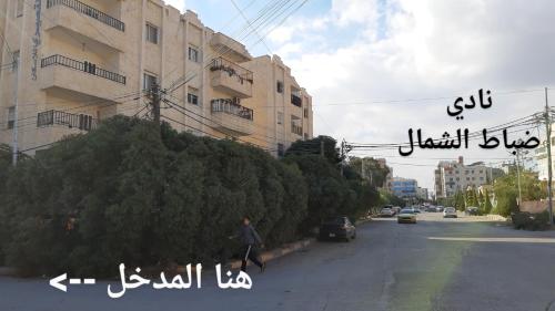 a man walking down a street next to a building at شقة مفروشة مجهزة بكل الخدمات in Irbid
