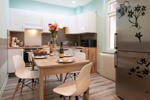 une cuisine avec une table avec des chaises et un réfrigérateur dans l'établissement Evasion St Joseph Odysalis - Lit King Size - Parking - Proche Centre, à Colmar