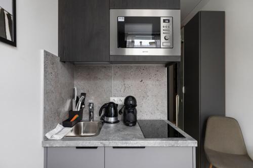 a kitchen with a sink and a microwave at Hook Studios Vilnius Old Town Economy in Vilnius