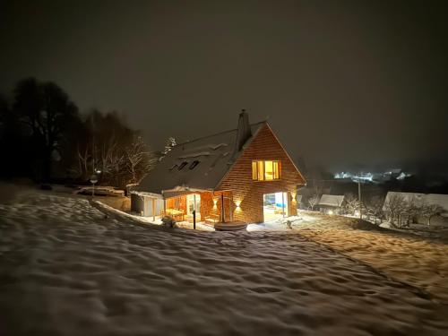 a wooden house in the snow at night at Villa Chalet Bledule-wellness & sauna in Roprachtice