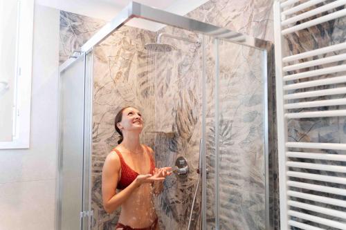 a woman is standing in a shower with a showerigunigunigunigunigunigun at Hotel Ascot Riccione in Riccione