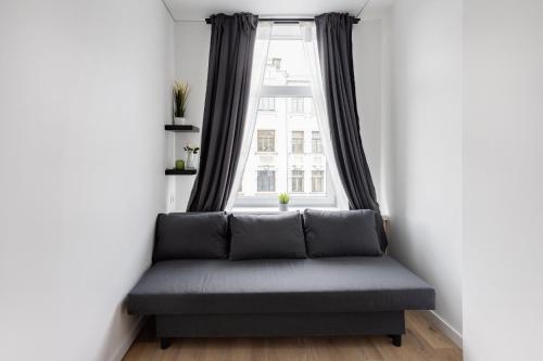 a couch in a room with a large window at Hook Studios Vilnius Old Town Economy in Vilnius