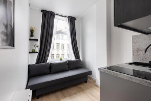 a living room with a couch in front of a window at Hook Studios Vilnius Old Town Economy in Vilnius