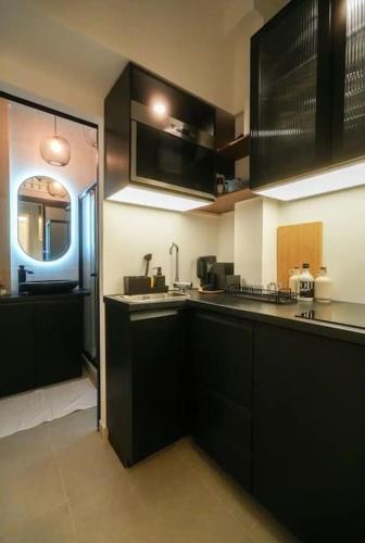 - une cuisine avec des placards noirs et un évier dans l'établissement Appartement parisien chic & cosy MBKA, à Paris