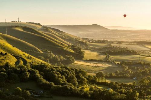 a hot air balloon flying over a valley with trees at The Retreat in Chelwood Gate