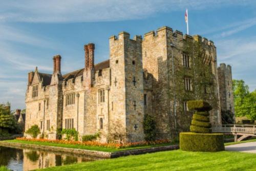 a large stone castle with a river in front of it at The Retreat in Chelwood Gate