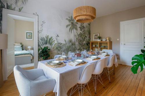 - une table à manger avec une nappe et des chaises blanches dans l'établissement Appartement Les Fougères Vittel 1e, à Vittel