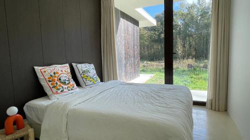 une chambre avec un lit et une grande fenêtre dans l'établissement Chambre privée dans maison d'architecte face forêt, à La Genevraye