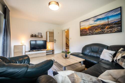 a living room with leather furniture and a flat screen tv at Ferienhaus Waldwinkl in Flachau