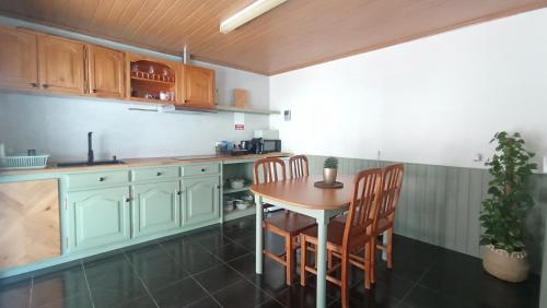 a kitchen with a wooden table and chairs in it at Kanela Guest House in Machico