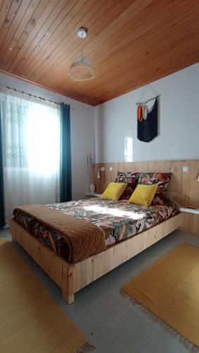 a large bed in a bedroom with a wooden ceiling at Kanela Guest House in Machico