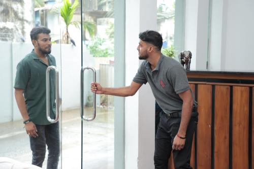 two men standing next to a bar with their hand on a door at Pearl Island Inn in Jaffna
