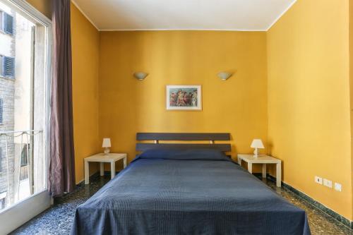 ein Schlafzimmer mit gelben Wänden und einem Bett mit zwei Tischen in der Unterkunft Bardi-Ponte Vecchio in Florenz