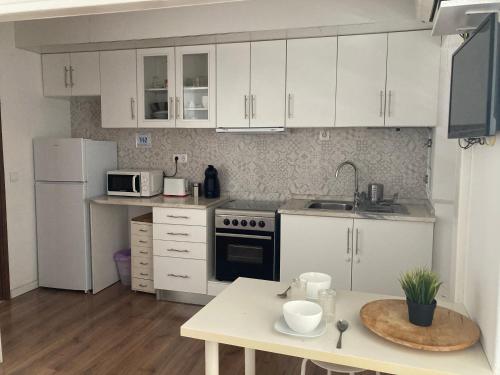 una piccola cucina con armadi bianchi e tavolo di Casa da Vila a Vila Nova da Barquinha